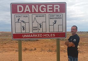 Chris in front of Coober Pedy Danger sign